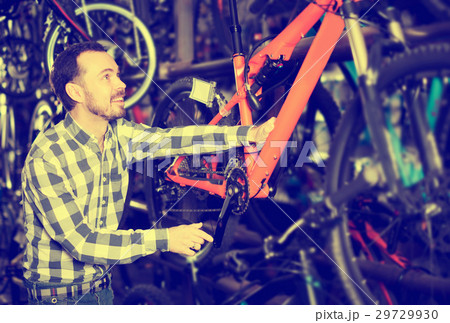 Man considers bicycle frame in store Man considers bicycle frame in store 29729930