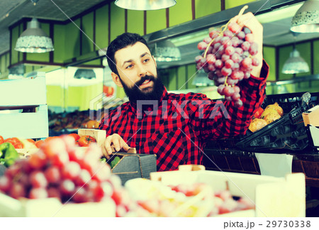 Shop assistant demonstrating grapes Shop assistant demonstrating grapes 29730338
