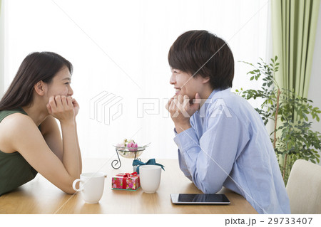 カップル男女 テーブルで向き合い笑顔で話す イメージの写真素材