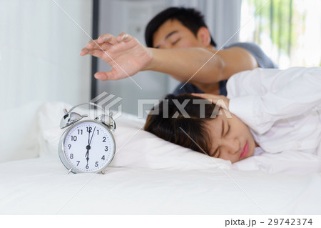 Sleepy man trying turn off alarm clock Sleepy man trying turn off alarm clock 29742374
