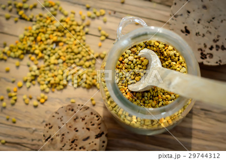 Grains of bee pollen in jar and wooden spoon on Grains of bee pollen in jar and wooden spoon on 29744312