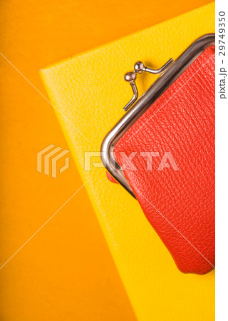 Orange wallet on a yellow notebook Orange wallet on a yellow notebook 29749350