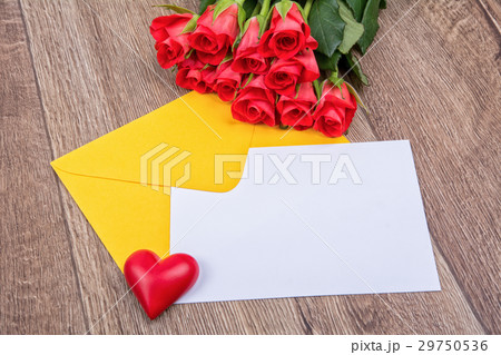 Yellow envelope, roses, heart and paper leaf on a wooden background 29750536