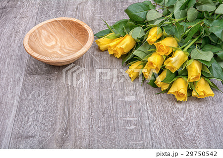 Yellow roses and a wooden bowl on a wooden background Yellow roses and a wooden bowl on a wooden background 29750542