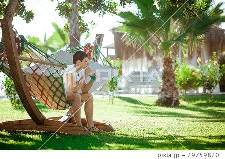 man in white shirt relaxing in hammock 29759820