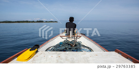 man sits on the front of a fishing boat looking at man sits on the front of a fishing boat looking at 29763385