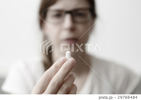 yound woman is eating pills or vitamin 29766484