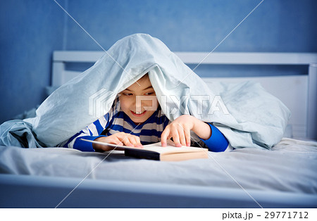 boy lying in bed with a book 29771712