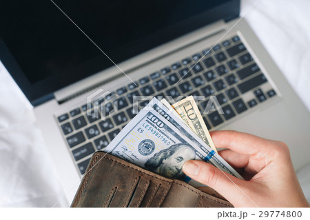Hands hold money over laptop, internet payments Hands hold money over laptop, internet payments 29774800