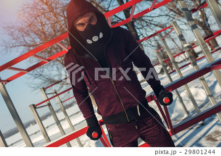 Young man in mask exercising on bars outdoors 29801244