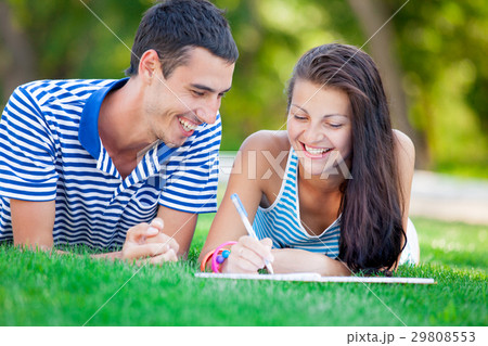 couple smiling and lying on the grass 29808553