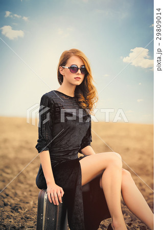 photo of beautiful young woman sitting on suitcase 29809014