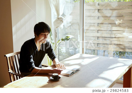 日当たりの良い部屋で読書をする男性。休日、日当たりの良いダイニングでくつろぐシーン。 日当たりの良い部屋で読書をする男性。休日、日当たりの良いダイニングでくつろぐシーン。 29824583