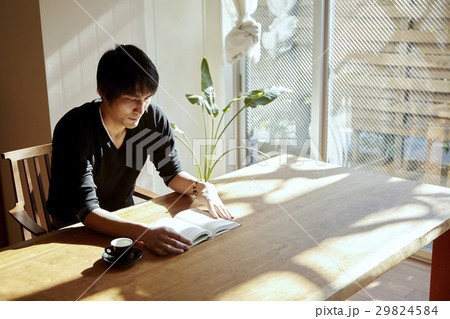 日当たりの良い部屋で読書をする男性。休日、日当たりの良いダイニングでくつろぐシーン。 29824584