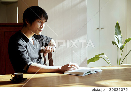 日当たりの良い部屋で読書をする男性。休日、日当たりの良いダイニングでくつろぐシーン。 29825076