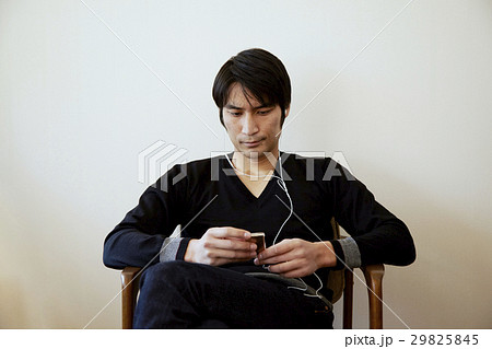 音楽を聴く男性。白壁バック。 音楽を聴く男性。白壁バック。 29825845