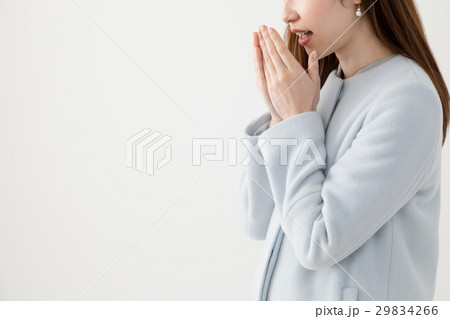 コートを着る女性 息を吐くの写真素材