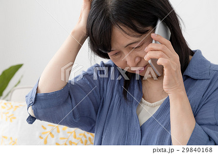 頭を抱えて電話をする女性 29840168