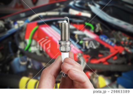 Mechanic holds a spare part spark plug in hand 29863389