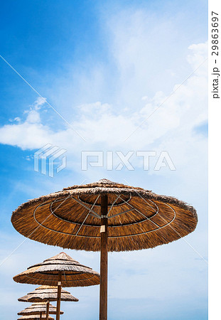 straw parasols and blue sky on beach 29863697