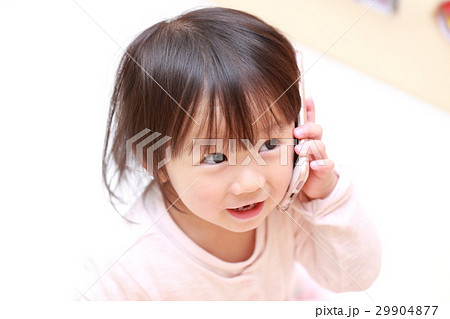赤ちゃん スマホ 携帯 電話 メール ベビー 幼児 女の子 1才 1歳 好奇心 興味 アイフォン の写真素材