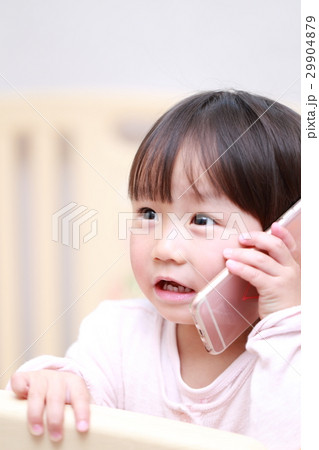 赤ちゃん スマホ 携帯 電話 メール ベビー 幼児 女の子 1才 1歳 好奇心 興味 アイフォン の写真素材