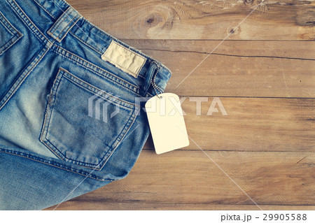 Blue jeans with white blank tag on wooden  29905588