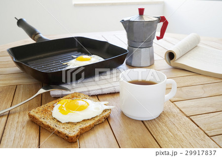 Fried eggs with toast, book and coffee 29917837