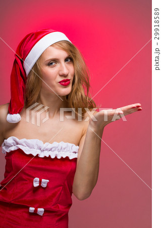 Attractive Christmas girl in santa hat on a red Attractive Christmas girl in santa hat on a red 29918589