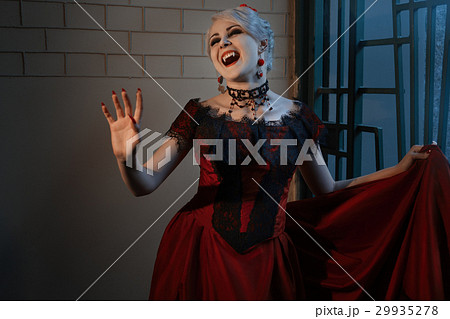 Woman in a red dress with a vampire grin. Woman in a red dress with a vampire grin. 29935278