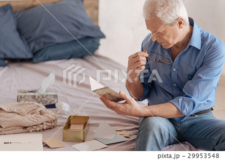 Serious elderly man reading an old postcard 29953548
