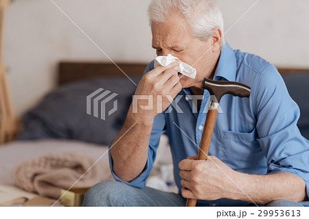 Moody aged man blowing his nose 29953613