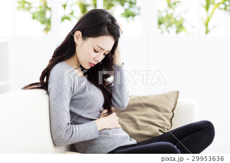 Young woman sitting on sofa and having stomachache 29953636