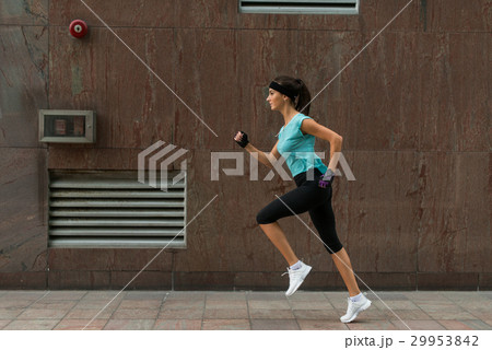 Side view of sporty young woman running on a Side view of sporty young woman running on a 29953842