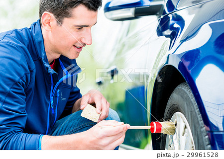 Man cleaning the alloy hubs on his car tyres 29961528