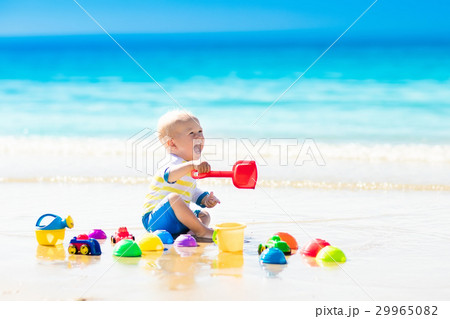 Baby playing on tropical beach digging in sand 29965082