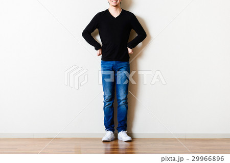 部屋の壁の前に立っている男性,ジーンズ 部屋の壁の前に立っている男性,ジーンズ 29966896