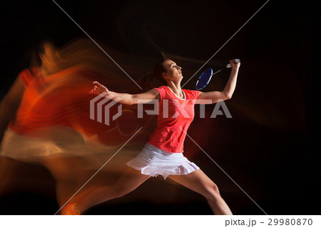 Young woman playing badminton over black 29980870