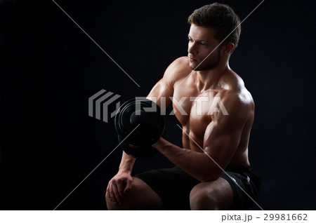 Muscular young man lifting weights on black Muscular young man lifting weights on black 29981662