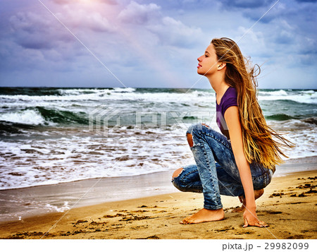 Girl on in sand beach looks thoughtfully into Girl on in sand beach looks thoughtfully into 29982099