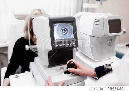 Women looking at eye test machine in ophthalmology 29988894