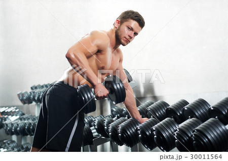 Handsome young athlete working out at the gym  30011564