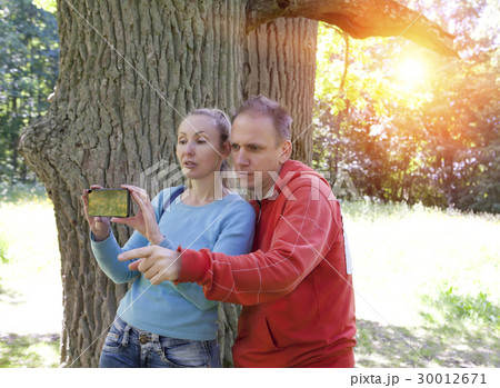 man and  woman near an oak in summer  day show to  30012671