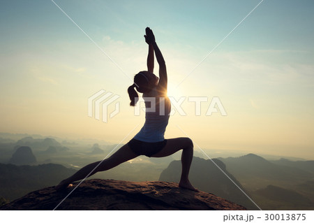 young woman meditating on sunrise mountain peak 30013875