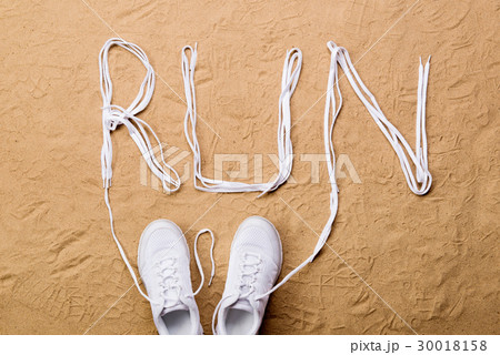 Running shoes and run sign made of shoelaces, sand 30018158