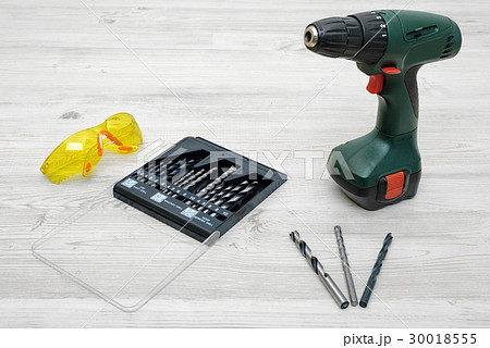 A cordless drill set to stand on a wooden table 30018555