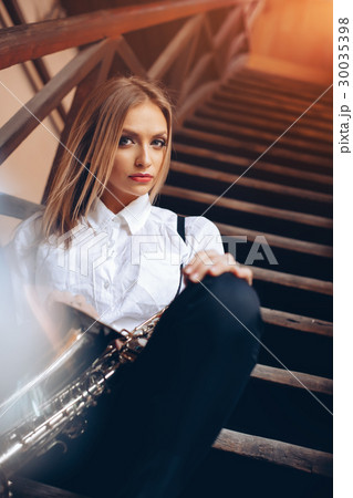 Young girl sitting on steps with a saxophone 30035398