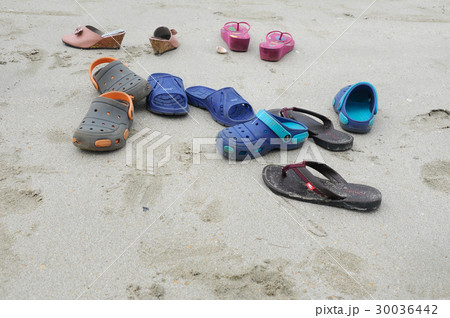 Pairs of children's slippers on beach Pairs of children's slippers on beach 30036442
