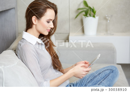 Attractive woman using digital tablet on sofa 30038910