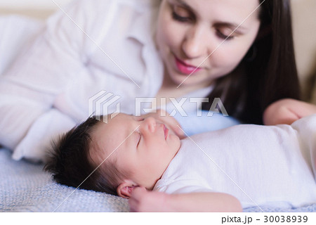 Happy young mother near sleeping baby 30038939